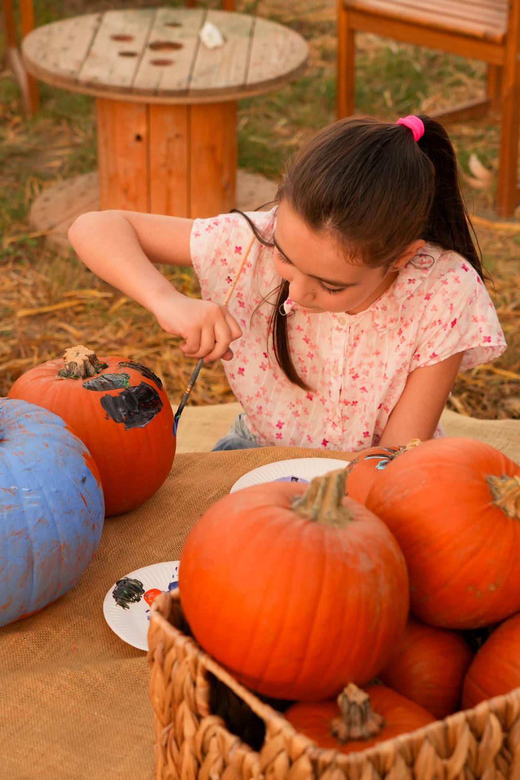 Una bambina lavora la sua zucca al tavolo del laboratorio, accanto a un cesto pieno