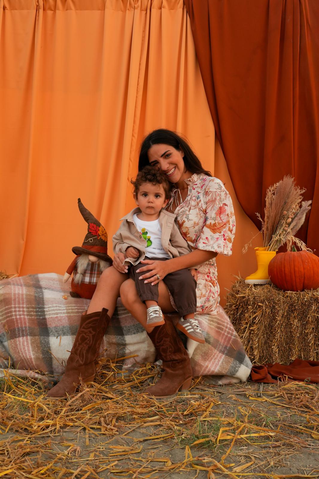 Mamma e bambino sulle balle di fieno, fra coperte a quadri e decorazioni di stagione