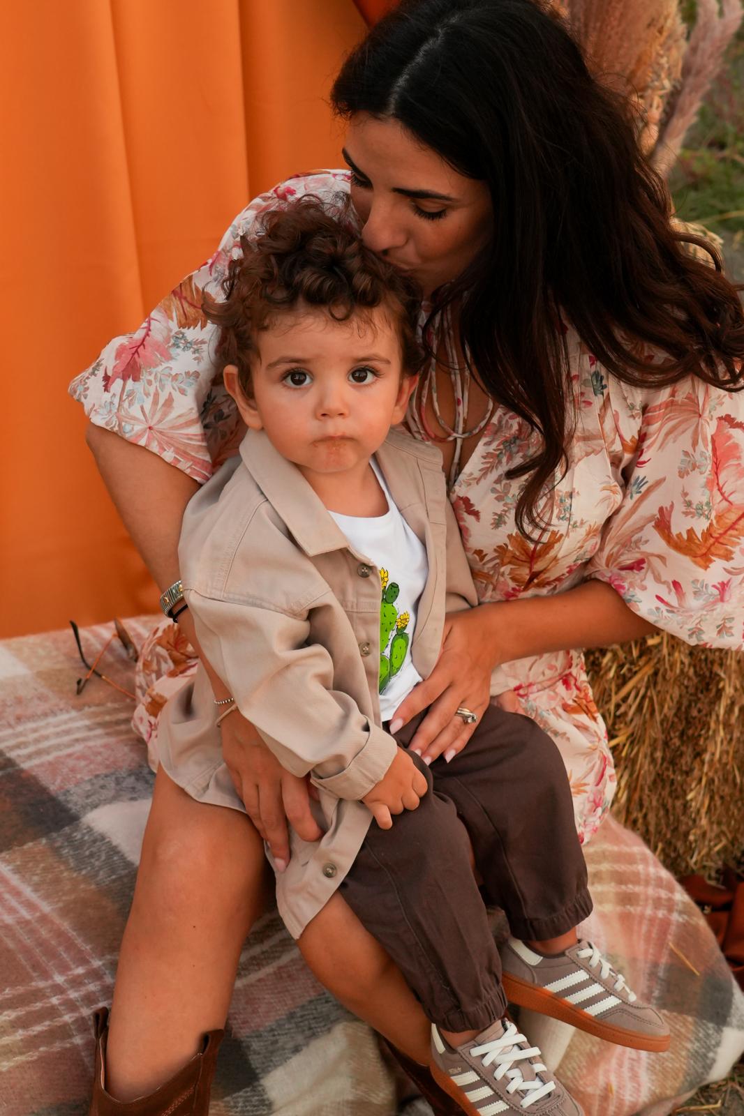Una mamma abbraccia il suo bambino seduta fra le decorazioni autunnali